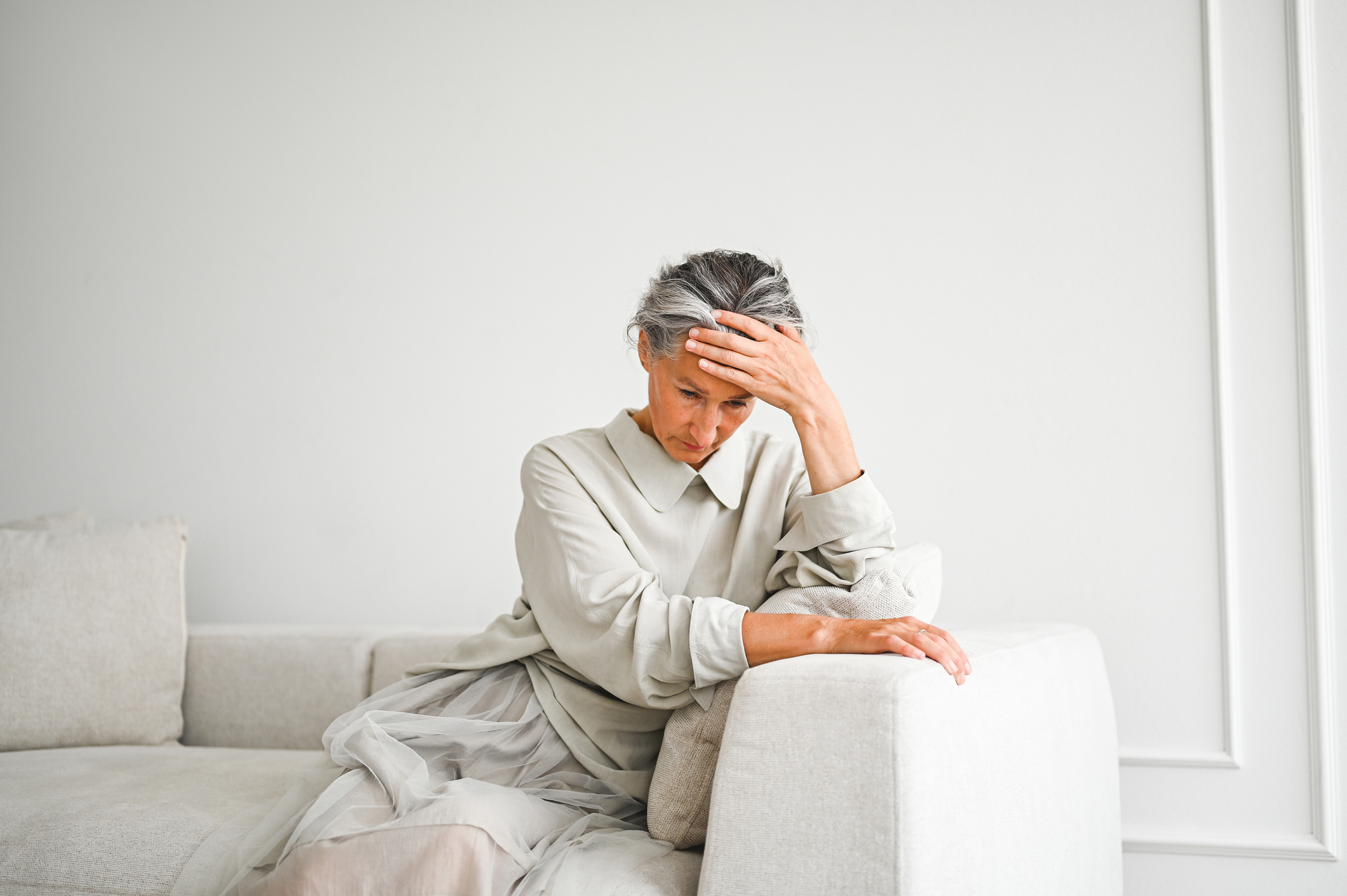 Frau sitzt erschöpft auf einem Sofa – Stress kann Histaminbeschwerden verstärken